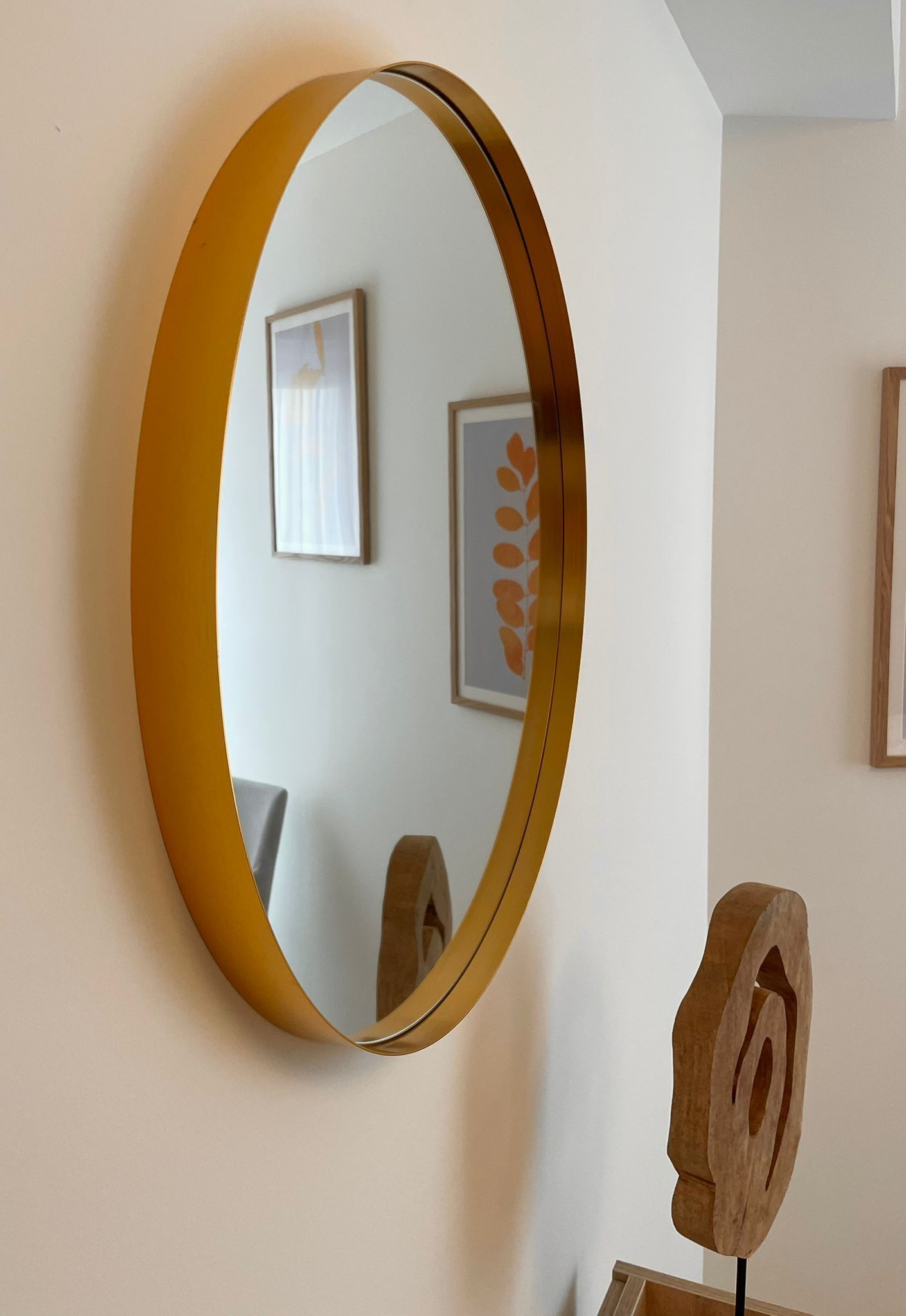 Un miroir rond, doté d’un cadre doré, fixé au mur.