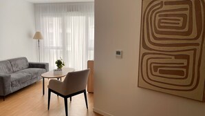 A modern living room with a grey sofa, a round table, and a minimalist artwork on the wall. -  ZENAO Appart'hôtels Dijon (Dijon)