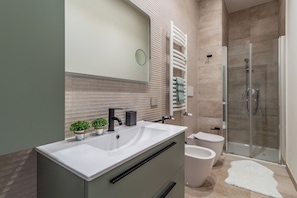 A modern bathroom with a large sink, a glass shower enclosure, and a toilet.