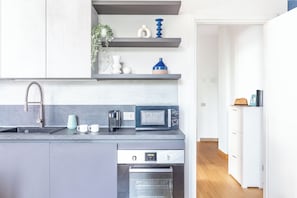 Una cucina moderna con forno integrato, microonde, lavello e macchina del caffè.