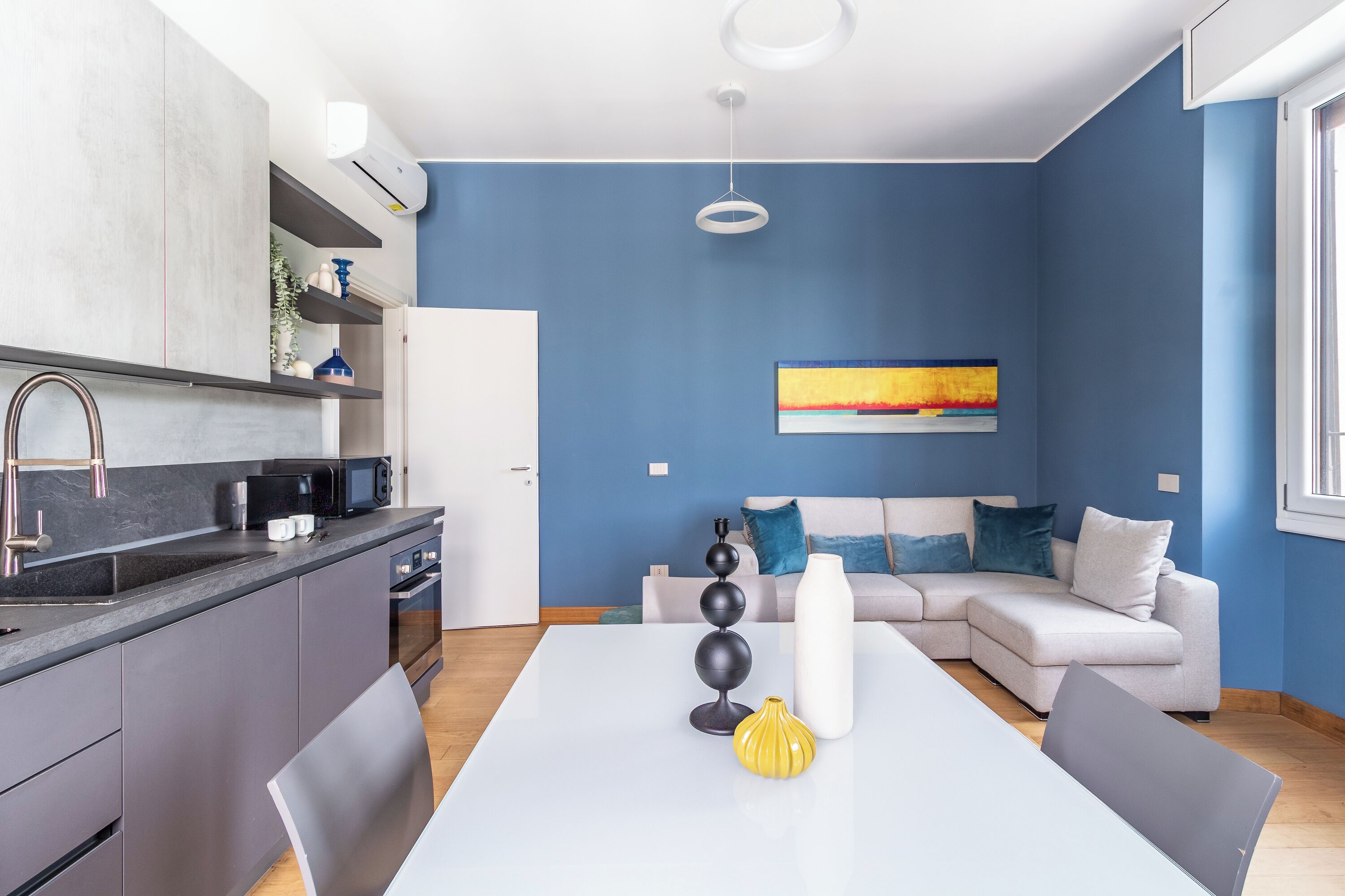 A modern kitchen with grey cabinets, a white countertop, and a built-in microwave.