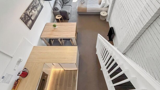 Een modern interieur met een houten eettafel, een bank en een bed met een witte kap.