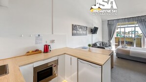 Een moderne keuken met een magnetron, waterkoker en een klein eethoekje.