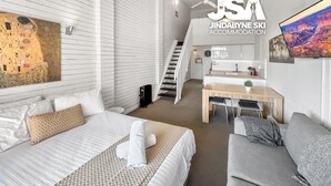 Een moderne hotelkamer met een groot bed, een bureau en een trap naar een balkon.