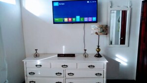 A white dresser with a flat-screen TV mounted above it displaying a home screen. - Cozy 3 Apartment — Penthouse in the Heart of Ochi (Ocho Rios)