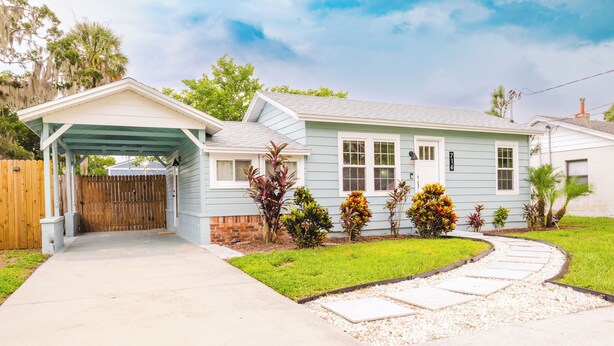 A single-story house with a covered porch, a front yard with a gravel pathway, and a wooden fence.