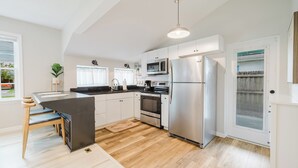 A modern kitchen with white cabinets, stainless steel appliances, and a wooden island.
