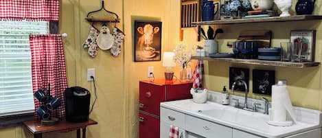 Una cocina con un letrero de granja, una cafetera, un armario rojo y una alfombra estampada.