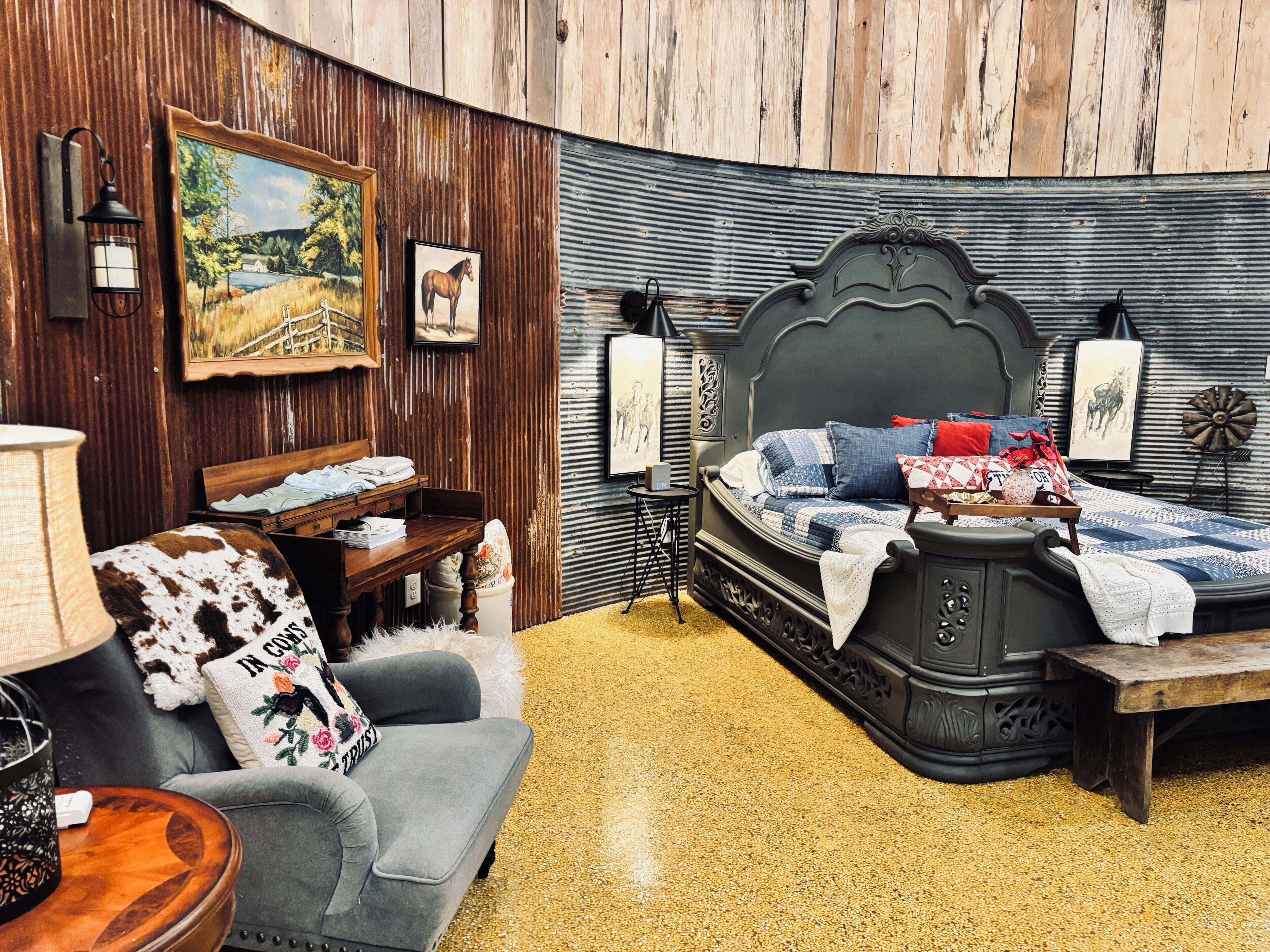 A bedroom with a bed, a sofa, a desk, and a lamp.