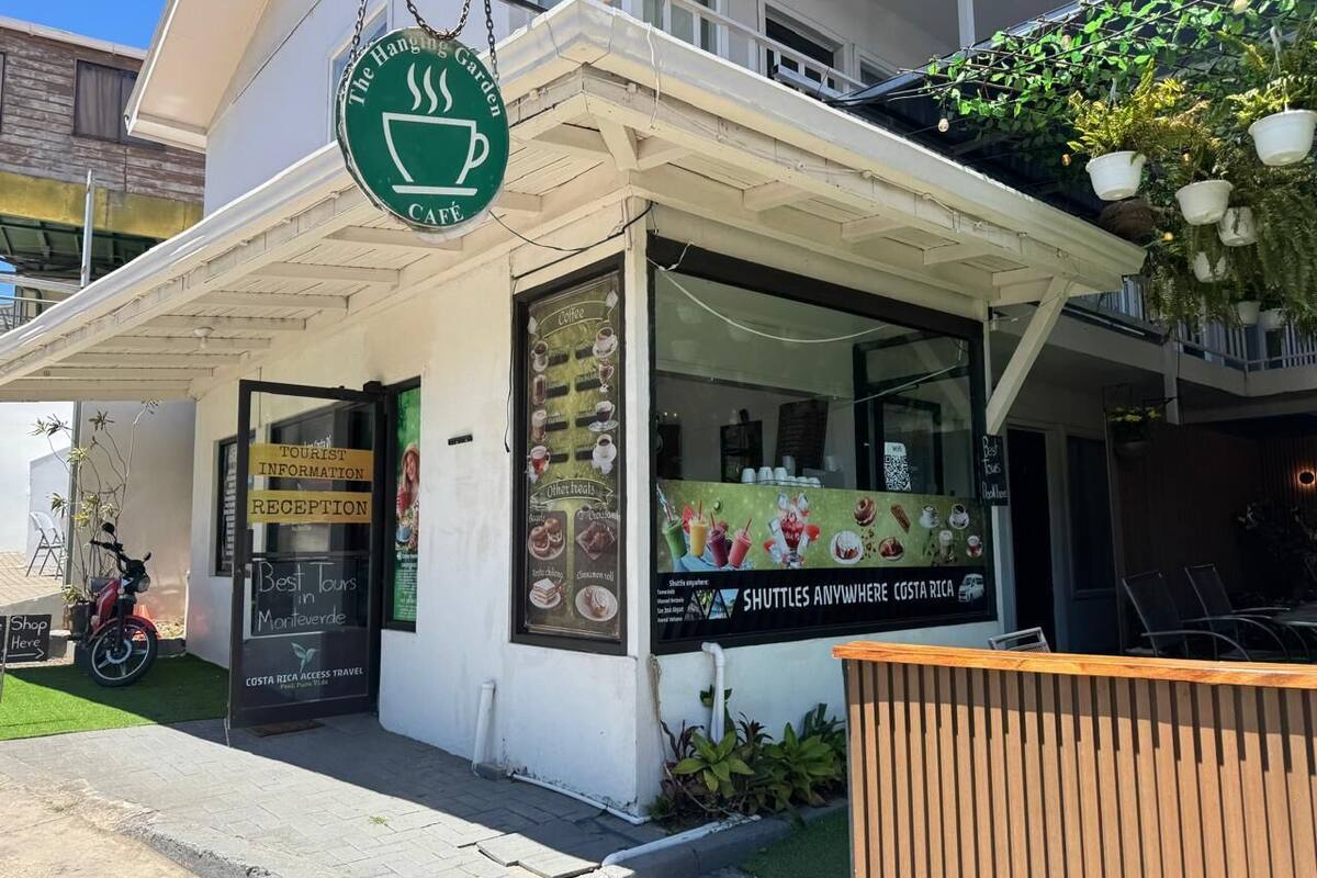 Un café avec une enseigne verte, une vitrine où sont exposés les plats proposés et un panneau indiquant le bureau d’information touristique.