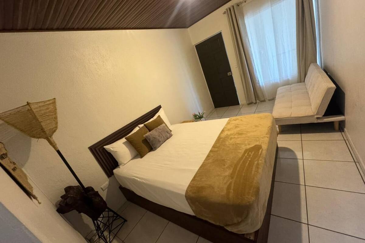 Une chambre d’hôtel avec un lit, un canapé, une lampe et une porte.