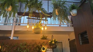 A balcony with hanging plants and lights, a wooden pergola, and a sign with 'Callejos' and 'Damas' visible. - Orchid Lodge Monteverde (Monteverde)