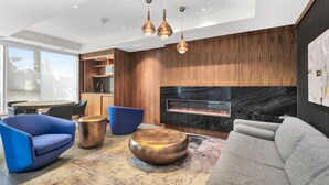 Una sala moderna con chimenea, sofás azules y grises, y una pared de acento de madera.