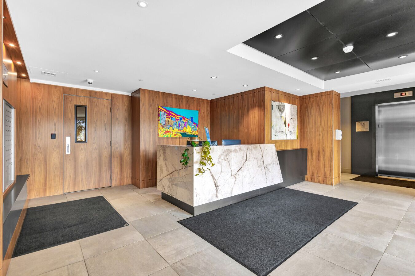 A reception area with a marble counter, wooden panel walls, and artwork.