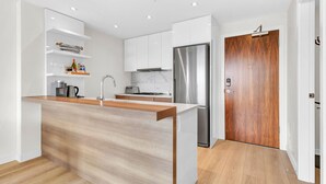 Una cocina moderna con armarios blancos, un refrigerador de acero inoxidable y una encimera de isla de madera.