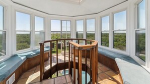 A sunroom with large windows, a wooden spiral staircase, and a view of the landscape. - Highest House in All of Fort Worth - Luxury Family Getaway with Stunning Views (Joshua)