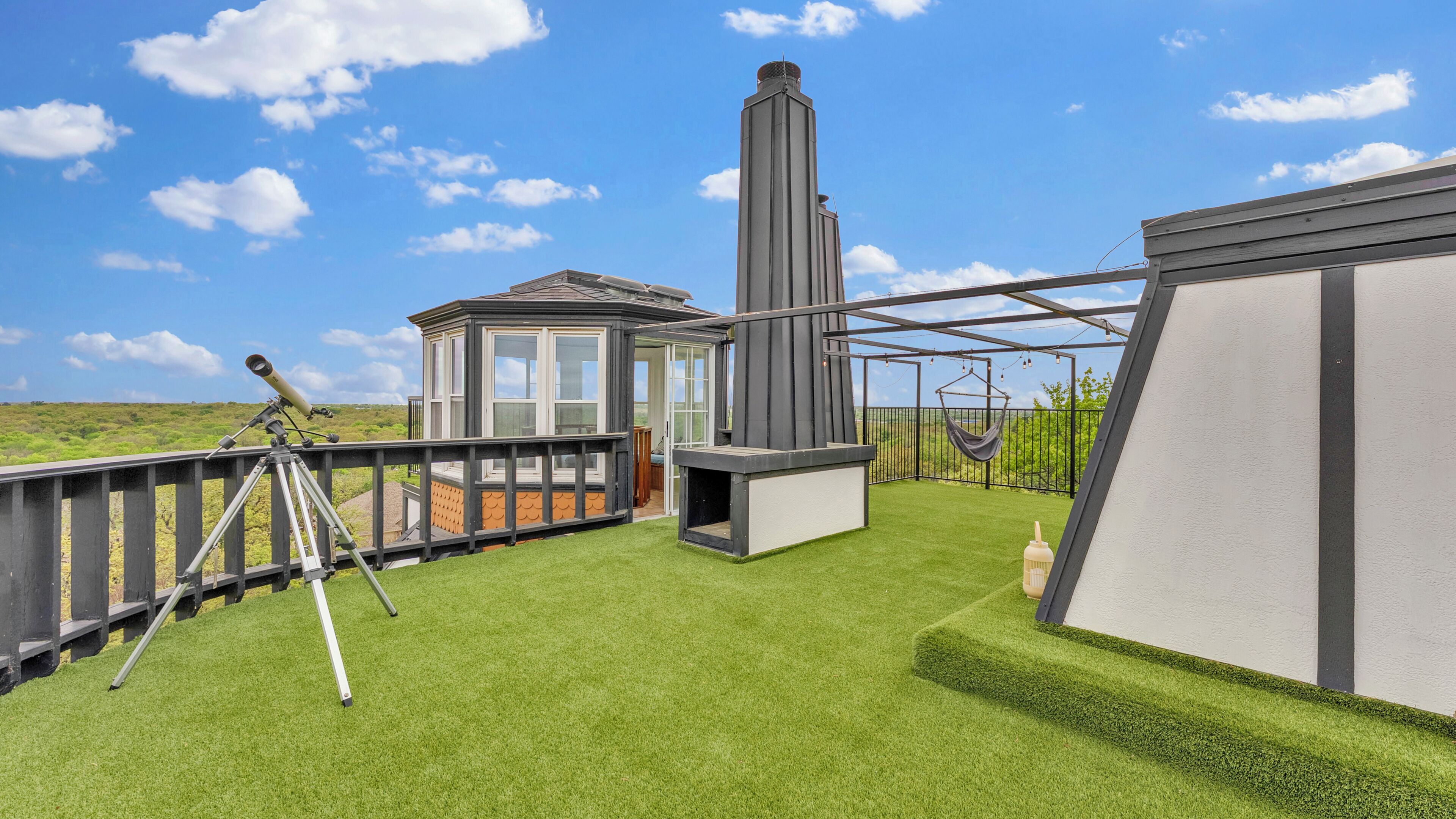 A rooftop terrace with a telescope, a chimney, and a hanging chair.