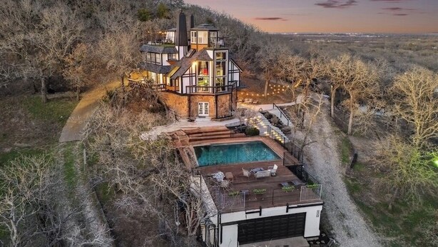 A large, multi-level house with a swimming pool, surrounded by trees and a hilly landscape. - Highest House in All of Fort Worth - Luxury Family Getaway with Stunning Views (Joshua)