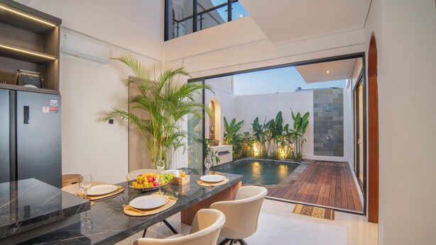 A modern kitchen with a dining area, a pool, and a view of the outdoors. - Nidya Villa Canggu (Canggu)