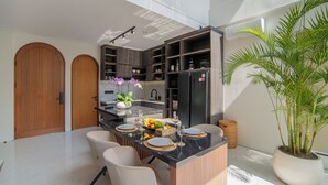 A modern kitchen with a central island, built-in appliances, and a large potted plant. - Nidya Villa Canggu (Canggu)