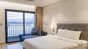 Ett modernt hotellrum med en stor säng, en balkong med utsikt och en sittgrupp med utsikt.