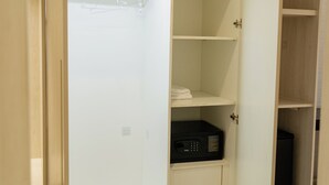 En walk-in-garderob med öppna dörrar, där hyllor och klädstänger syns.