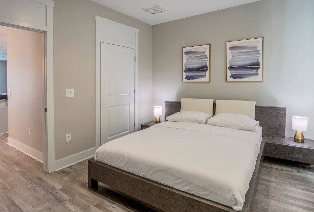 A bedroom with a bed, nightstands, and wall art.