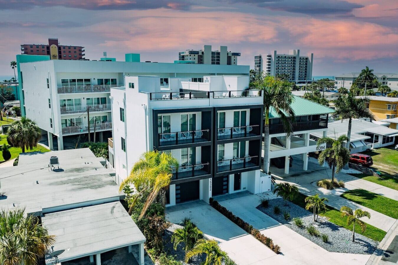 Un hotel moderno de varios pisos con balcones, una piscina en la azotea y vistas de la ciudad circundante.