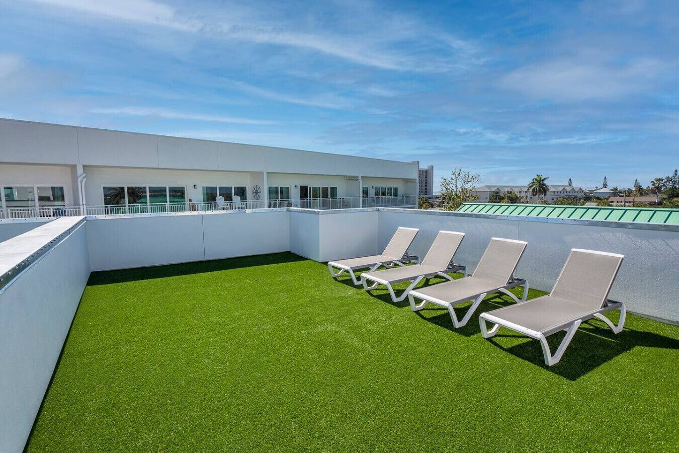 Une terrasse sur le toit, dotée d’un revêtement de gazon synthétique et de quatre chaises longues.