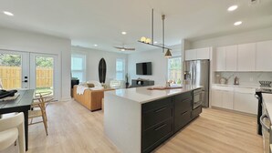 Une cuisine moderne dotée d’un îlot central, de meubles de rangement noirs et d’un réfrigérateur en acier inoxydable.