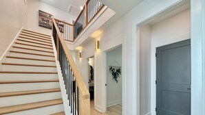 Un escalier moderne avec des marches en bois et des rampes noires, menant à un palier situé au deuxième étage.