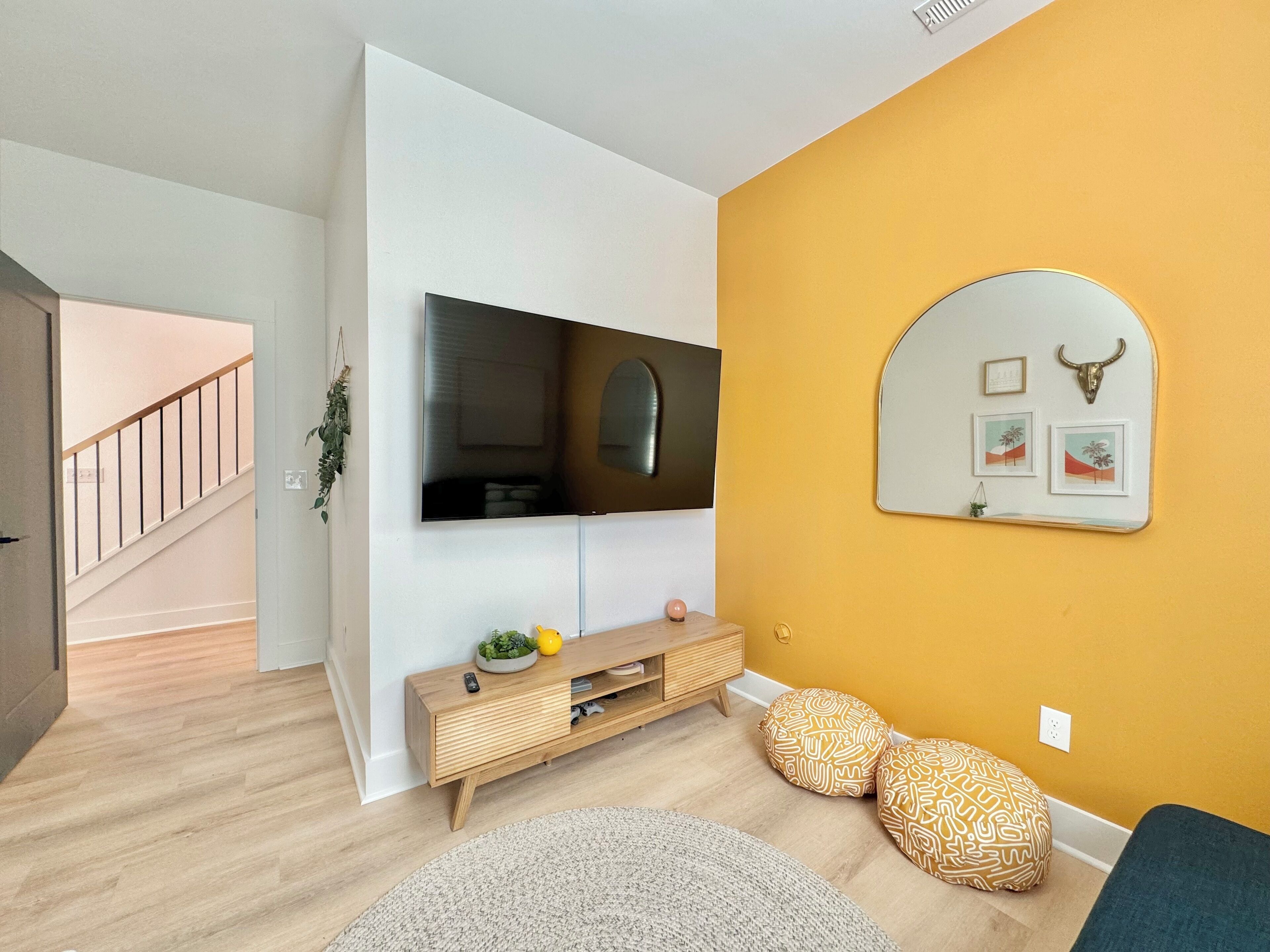 Una sala de estar moderna con un televisor de pantalla plana montado en la pared, una mesa consola de madera y un sofá.