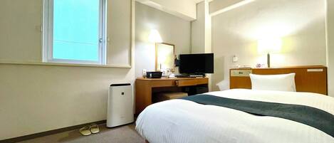 Una habitación de hotel con una cama grande, un escritorio con televisor, una lámpara y un teléfono.