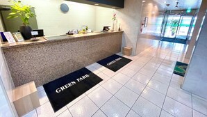 Ett entréområde med en receptionsdisk, en klocka, en krukväxt och en skylt med texten ”GREEN PARK”.
