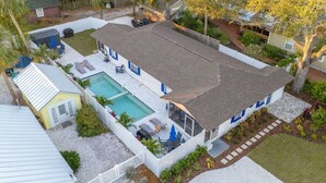 Ein zweistöckiges Haus mit Pool, umzäuntem Garten und einer kleinen Gartenhütte.