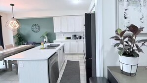 Une cuisine moderne avec des meubles blancs, un îlot central et un coin repas.