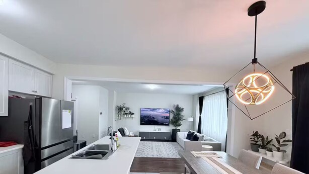 Une cuisine moderne dotée d’un îlot central, d’appareils électroménagers en acier inoxydable et d’un coin repas avec une longue table en bois.