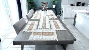 Une cuisine moderne avec des meubles blancs, un coin repas doté d’une table et d’un banc en bois, et une horloge murale décorative.