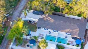 Eine Luftaufnahme eines Hauses mit Schwimmbad, Terrassenmöbeln und einem eingezäunten Garten.
