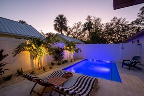 A backyard with a swimming pool, two lounge chairs, and a small table. - Downtown-Gulfport/Cooled Pool (Gulfport)