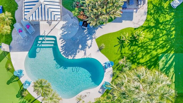 An aerial view of a swimming pool area with lounge chairs, a pathway, and surrounding greenery. - Tropical Paradise-4/4 (Largo)