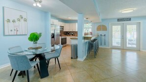 A spacious kitchen with modern appliances, a dining area with a glass table, and a bar area with stools. - Tropical Paradise-4/4 (Largo)