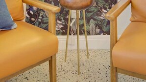 A room with two leather chairs, a wooden bowl on a small stool, and a wall with a floral pattern and a neon sign that reads "This is our happy place." - Palm Oasis 2/2 Serene Backyard Private Poolside (St. Petersburg)