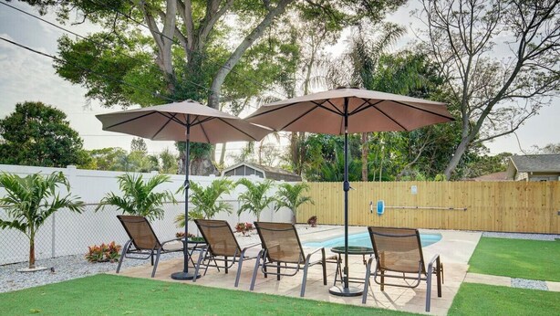 A backyard with a pool, four lounge chairs, and two umbrellas. - Palm Oasis 2/2 Serene Backyard Private Poolside (St. Petersburg)