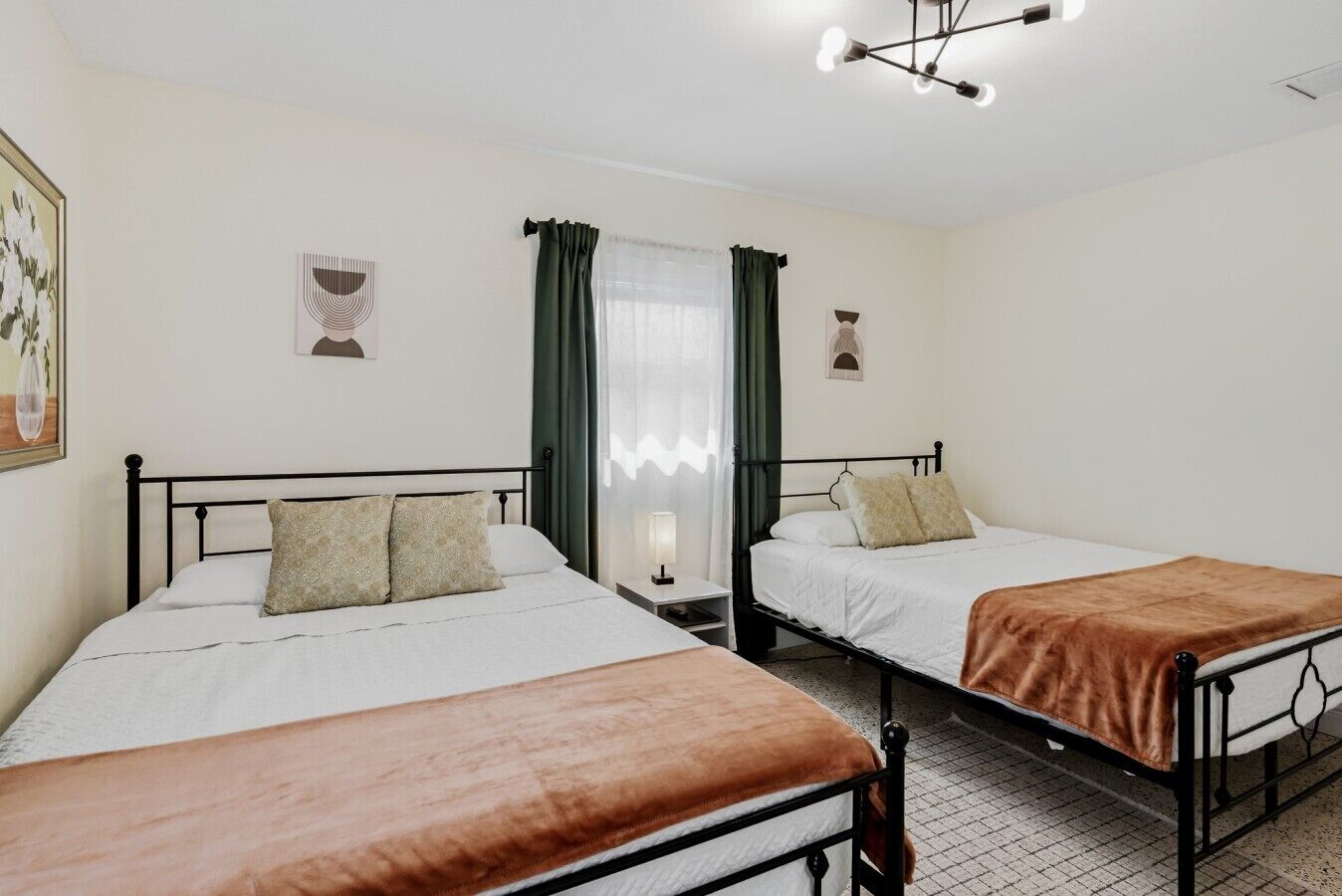 Ein Hotelzimmer mit zwei Betten, einem Nachttisch, einer Lampe und einer Deckenleuchte.