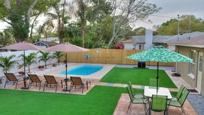 A backyard with a swimming pool, patio furniture, and a well-maintained lawn. - Palm Oasis 2/2 Serene Backyard Private Poolside (St. Petersburg)