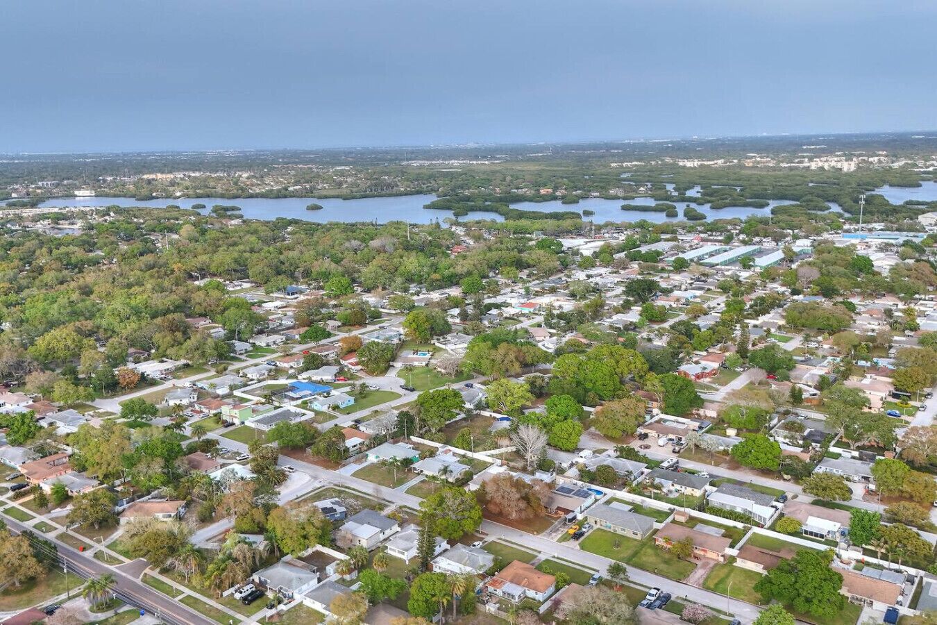 Ovenudblik over et boligområde med huse, veje og et stort vandområde i baggrunden.
