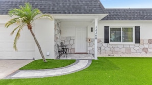 A single-story house with a stone facade, a white garage door, and a number '12260' on the wall. - Chic Coastal Getaway (Largo)