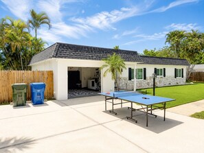 Een wooneiland met een overdekt terras, een tafeltennistafel en een omheinde tuin.