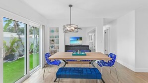 A dining area with a wooden table, blue upholstered chairs, and a bench. - Chic Coastal Getaway (Largo)